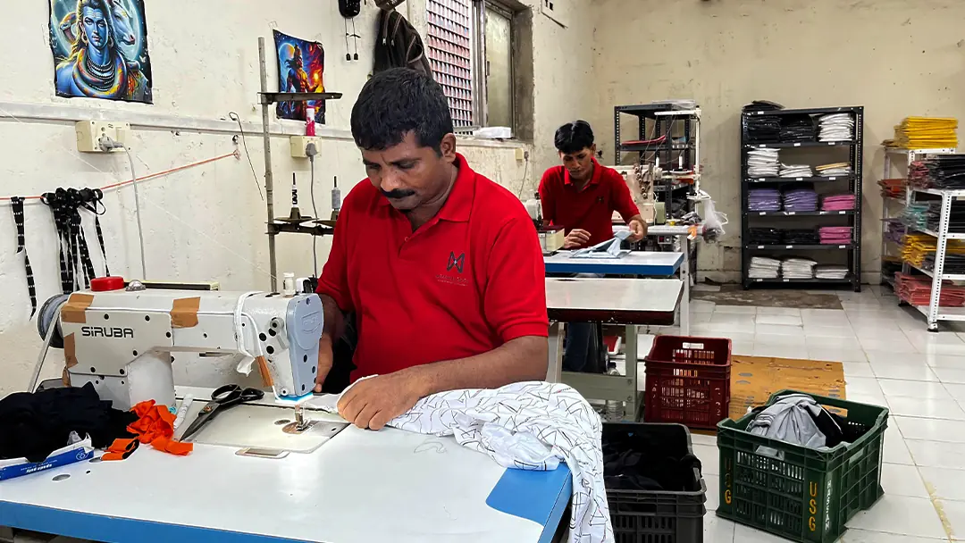 A tailor stitching at a sewing machine on the Minimalistic Garments production floor